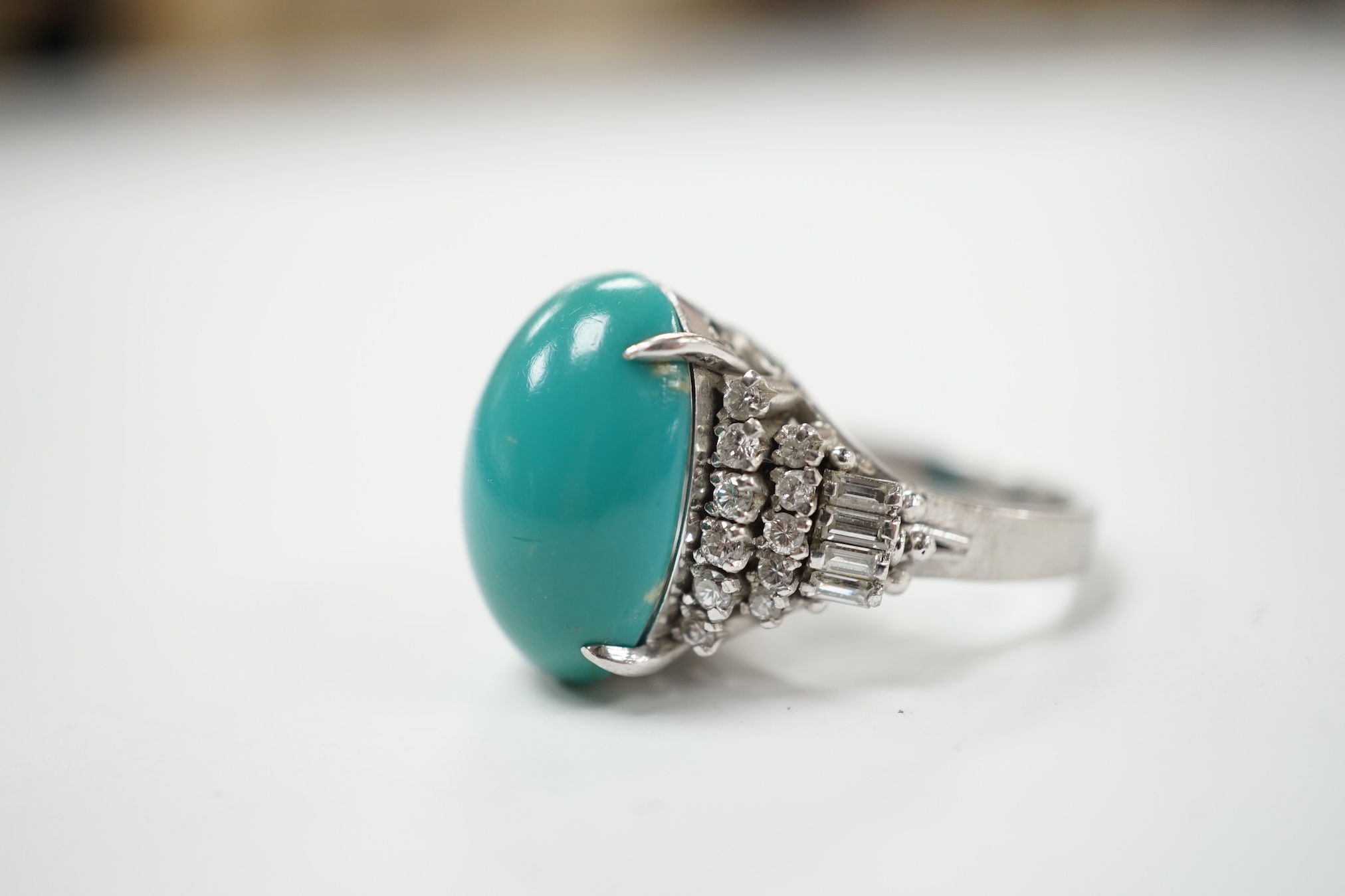 A modern white metal (stamped Pt900) and cabochon turquoise set dress ring, with baguette and round cut diamond set shoulders, size M, gross weight 12.4 grams. Condition - fair